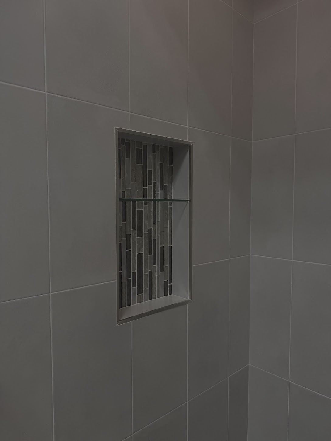 Close view of a tiled shower niche with mosaic accent