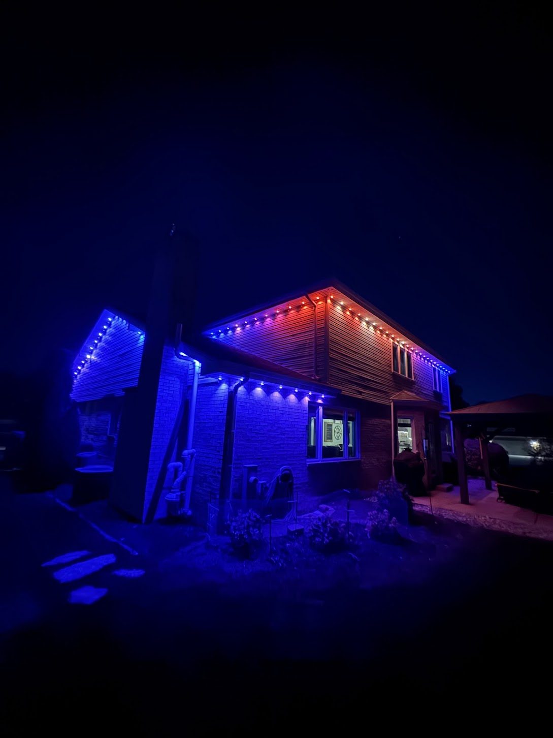 House at night with red, white, and blue permanent roofline lighting